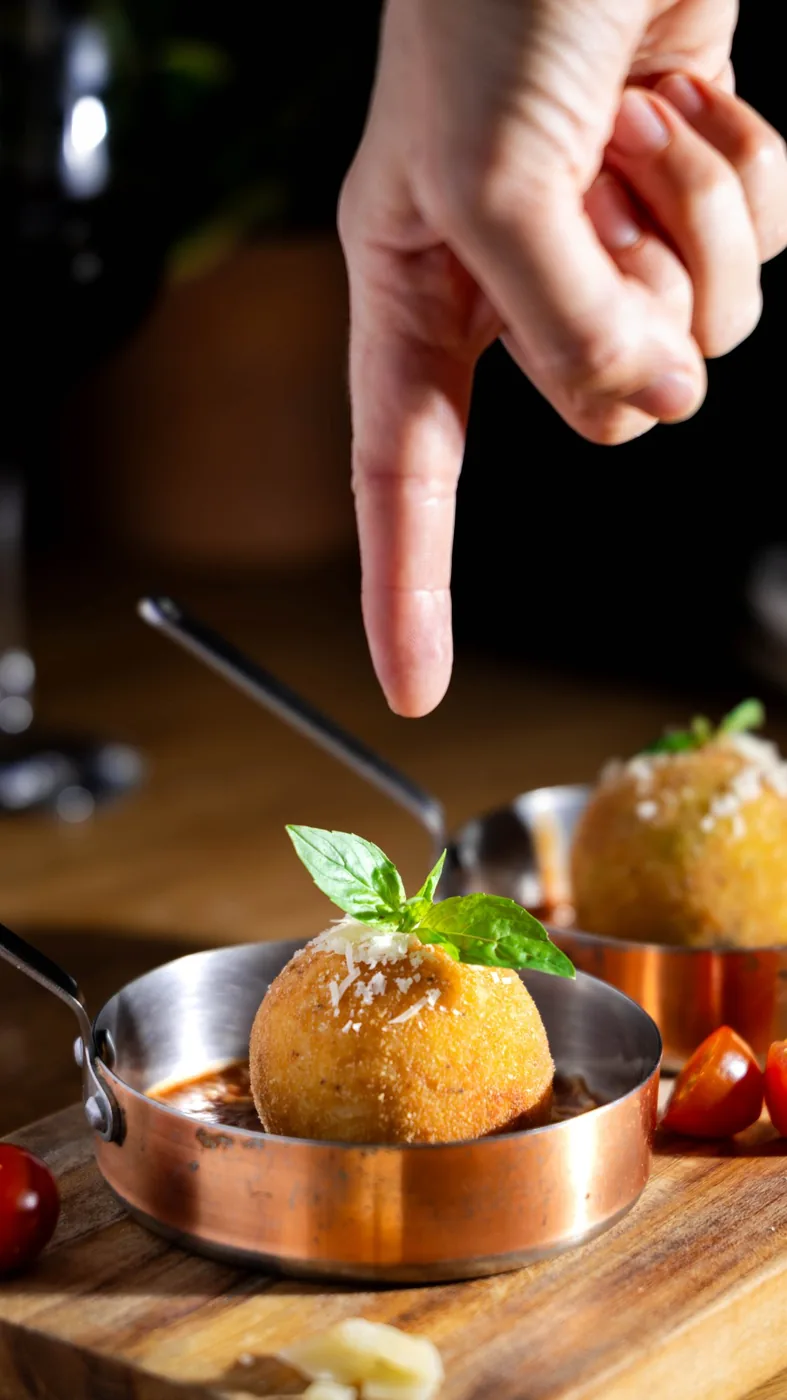 A hand points to an arancino